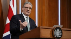 木製の演壇を前に話すスターマー氏。背後にはイギリス国旗が立てられている