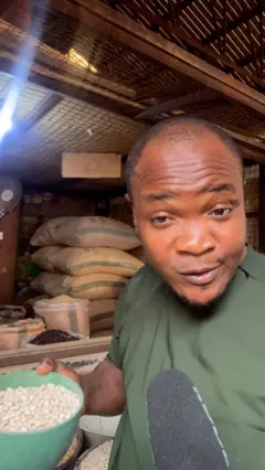 A male presenter carrying a bowl of beans
