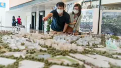 ภาพชายดูโมเดลผังเมืองของสิงคโปร์