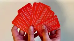 Hands holding red cards in various languages.
