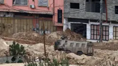 مركبة إسرائيلية في طريق مدمر في مخيم نور شمس بسبب المداهمات الإسرائيلية. الصورة التقطت نهاراً