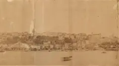 Aparentemente uma fotografia em tom sépia mostra mar e casas de Salvador