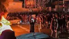 Люди на вулиці в темряві, палає багаття