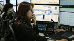 モニターを見つめるアジア系の女性が口元を手で押さえている。