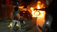 Policial com cachorro passajoguinho que não precisa baixarfrente a carro pegando fogojoguinho que não precisa baixarprotesto