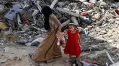 Ғазо вайроналарида кутаётган муслима аёл ва қизи