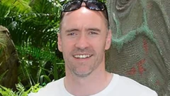 Peter Doyle'un fotoğrafı, kafasında güneş gözlüğü var, saçları az olmasına karşın genç bir görüntüsü var ve tebessüm ederek poz veriyor.