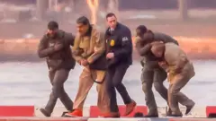 Rettenu par des gardes en uniforme, le président vénézuélien Nicolás Maduro arrive menotté à l'héliport du centre de Manhattan avant sa comparution devant le tribunal fédéral de New York, aux États-Unis, le 5 janvier 2026.