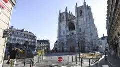 A man stares up at the charred front of the cathedral in Nantes