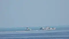 Chinese Coast Guard boats close to the floating barrier are pictured near the Scarborough Shoal