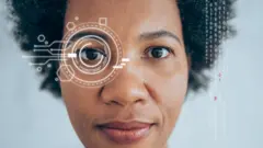 Une femme noire regarde directement dans l'objectif de l'appareil photo sur une photo avec des graphiques superposés indiquant "scanning".