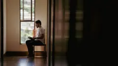 Kaik Ribas lendro um livro sentado de lado numa cadeira