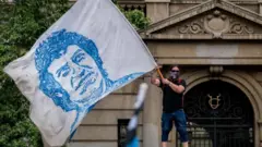 Homem agita uma bandeira com a imagem de Víctor Jara
