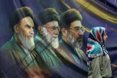 Mujer camina en Irán frente a cartel con los ayatolás