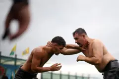 dva muškarca bez majica, namazani uljem, se rvu na turniru u bugraskoj.