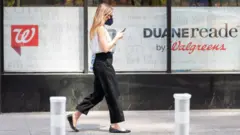 Woman walks in front of a Walgreens