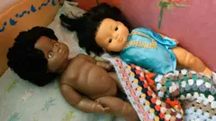 Deux poupées allongées sur un lit.