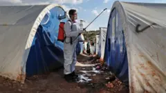 A member of the Syrian Violet NGO disinfects tents at a camp for displaced people in Kafr Jalis village, north of Idlib city, on March 21, 2020