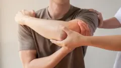 A medical professional checking a man's elbow