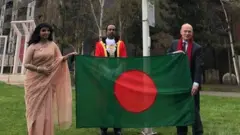 আলতাব আলী পার্কে বাংলাদেশের পতাকা উত্তোলন অনুষ্ঠান। পতাকা ধরে আছেন হাইকমিশনার সাঈদা মুনা তাসনিম এবং মেয়র জন বিগস্‌।