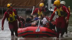 Bombeiros usam bote para resgatar pessoas ilhadas em enchente