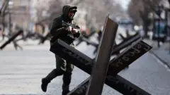 Um integrante do serviço ucraniano passa por uma barricada antitanque no centro de Odessa, Ucrânia, 20 de março de 2022