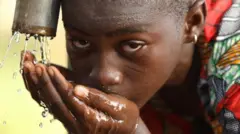 Wata yarinya na shan ruwan burtsatse a kauyen Mogolu na Ghana