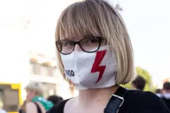 ผู้หญิงสวมหน้ากากมีรูปสายฟ้าฟาดสีแดง