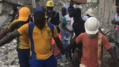 Ndị ọrụ gbatagbata na-ebuta ndị tọọ n'okpuru ụlọelu dara n'Ikoyi