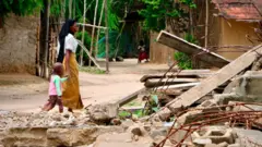 Nanduadua residents walk past the rubble and debris of a mosque allegedly destroyed by Mozambican forces