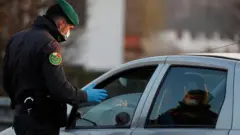 A member of the Guardia di Finanza wearing a face mask stops a car, amid a coronavirus outbreak in northern Italy