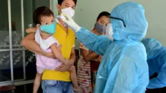 A family have their temperatures taken in Da Nang, Vietnam