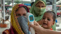 নতুন দিল্লিতে বাসে ওঠার আগে একজন নারীর তাপ চেক করা হচ্ছে, ০৩/০৮/২০২০।