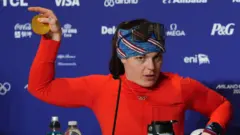 Бріззі Джонсон показує зломану медаль 