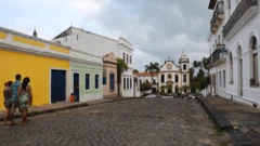 Varias personas caminan entre edificios coloridos en la ciudad de Olinda, en el noreste de Brasil, hacia la Basílica del Monasterio de San Benito.