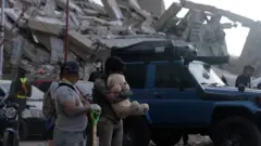 Familiares dos migrantes que foram deportados no voo 164 dos Estados Unidos para a Venezuela, no dia dos dois terremotos (24/6), no lado de fora dos edifícios que desabaram em La Guaira