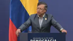 Gustavo Petro falando ao microfone em um púlpito. Atrás está a bandeira da Colômbia