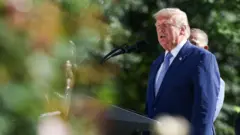 Donald Trump discursando em um evento, vestindo terno e gravata azuis