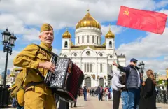 Um homem segura uma bandeira soviética.