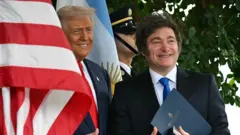 Donald Trump e Javier Milei, com as bandeiras dos Estados Unidos e da Argentina