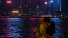 一對情侶在香港維多利亞海港前相擁接吻。