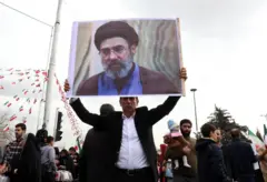 Un hombre sostiene un cartel con la foto de Mojtaba Jamenei