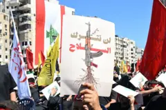 لافتة كُتب عليها "لن نترك السلاح" بيد أحد أنصار حزب الله في بيروت ضمن مسيرة حاشدة في إحياء ذكرى عاشوراء في الضاحية الجنوبية 2025.