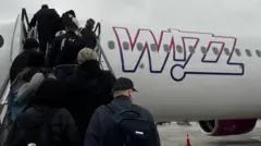 Ludzie wsiadają do samolotu Wizz Air w mglisty poranek na lotnisku w Balicach koło Krakowa, w Polsce, 27 listopada 2024 r.