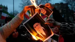 Manifestantes en Irán queman fotos de los dirigentes del régimen iraní.