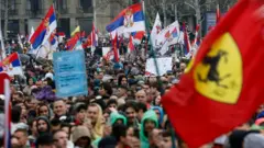 Manifestantes agitam bandeiras enquanto marcham em direção a Belgrado em 15 de março de 2025 em Belgrado, Sérvia.