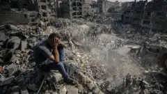 Un homme assis sur les décombres se tient la tête