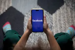 شعار تطبيق فيسبوك على هاتف ذكي بين يدين طفل