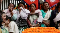 भदौ २४ गते मारिएका मानिसका परिवारजन को शोकाकुल मुद्रामा, उनीहरूले मृत व्यक्तिको तस्बिर बोकेका छन्, पृष्ठभूमिमा नेपालको झण्डा छ 