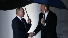 Путин и Алиев стоят под дождем с зонтиками в руках.